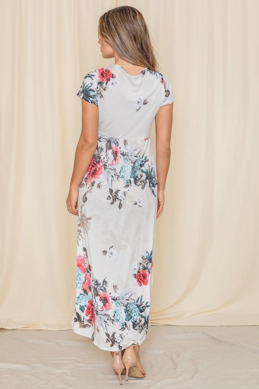 A woman posing in a short sleeve floral maxi gown. 