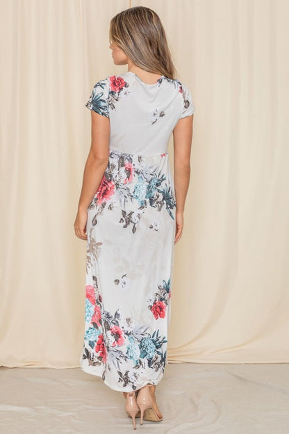 A woman posing in a short sleeve floral maxi gown. 