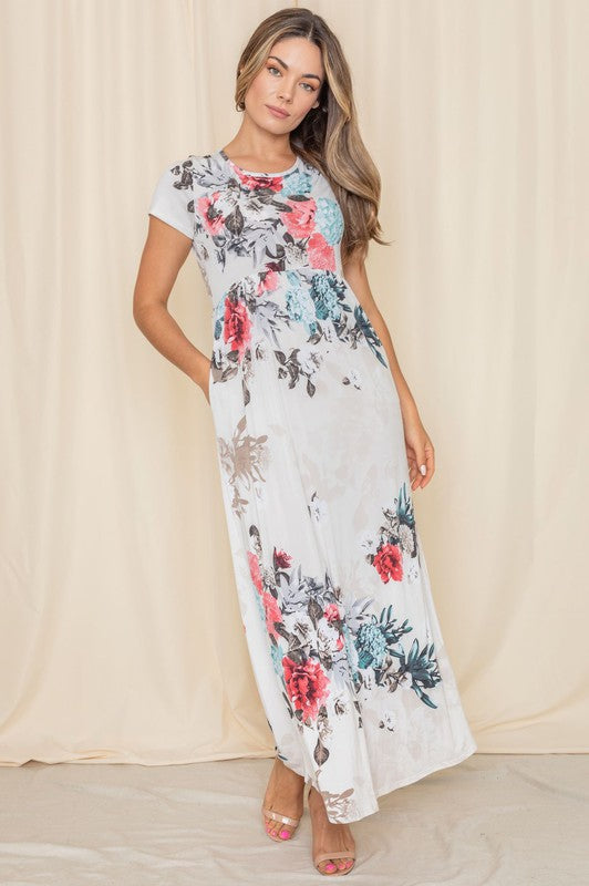 A woman posing in a short sleeve floral maxi gown. 