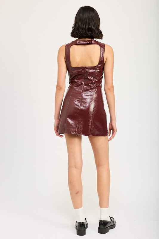 Woman wearing a sleeveless burgundy leather mini dress with squared neckline and open back.