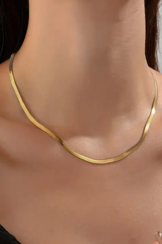 Lady wearing a sleek, minimalist gold necklace with a smooth, curved design, elegant, modern, and perfect for layering or solo statement styling.