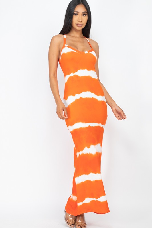 Woman wearing a sleeveless an orange and white tie-dye maxi dress with spaghetti straps, paired with white sneakers. 