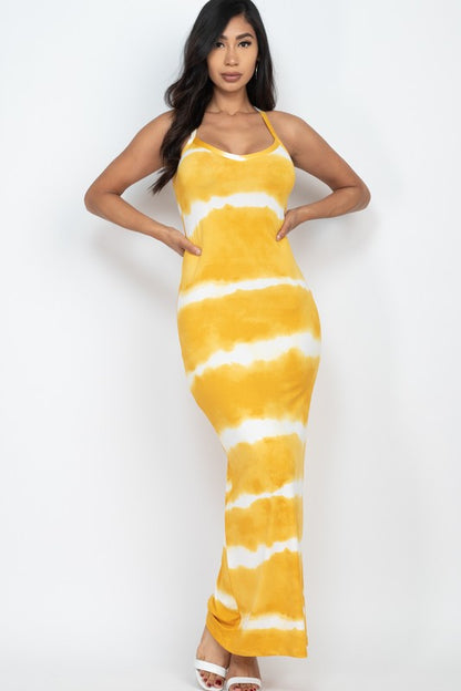 Woman wearing a sleeveless yellow and white tie-dye maxi dress with spaghetti straps, paired with white sneakers.
