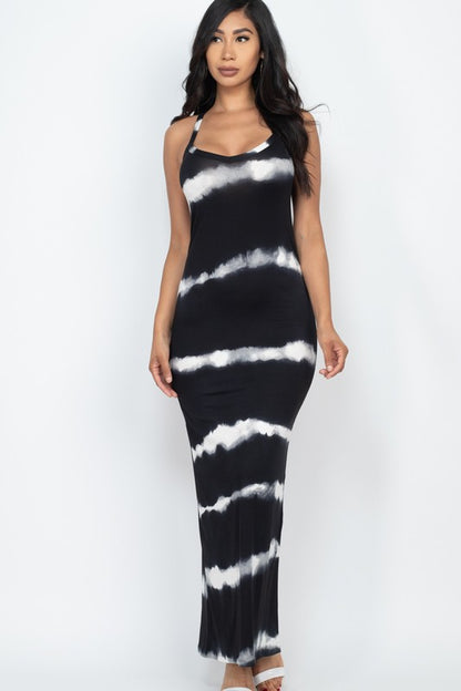 Woman wearing a sleeveless black and white tie-dye maxi dress with spaghetti straps, paired with white sneakers.
