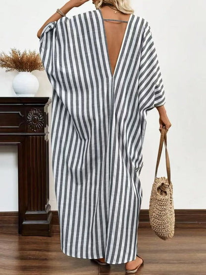 A woman rocking a chic gray and white striped maxi dress with a V-neck and loose sleeves.