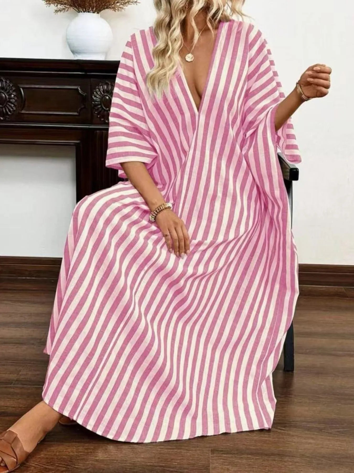 A woman rocking a pink and white striped maxi dress with a V-neck and loose sleeves.