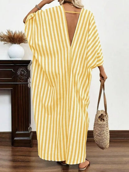 A woman rocking a yellow and white striped maxi dress with a V-neck and loose sleeves.