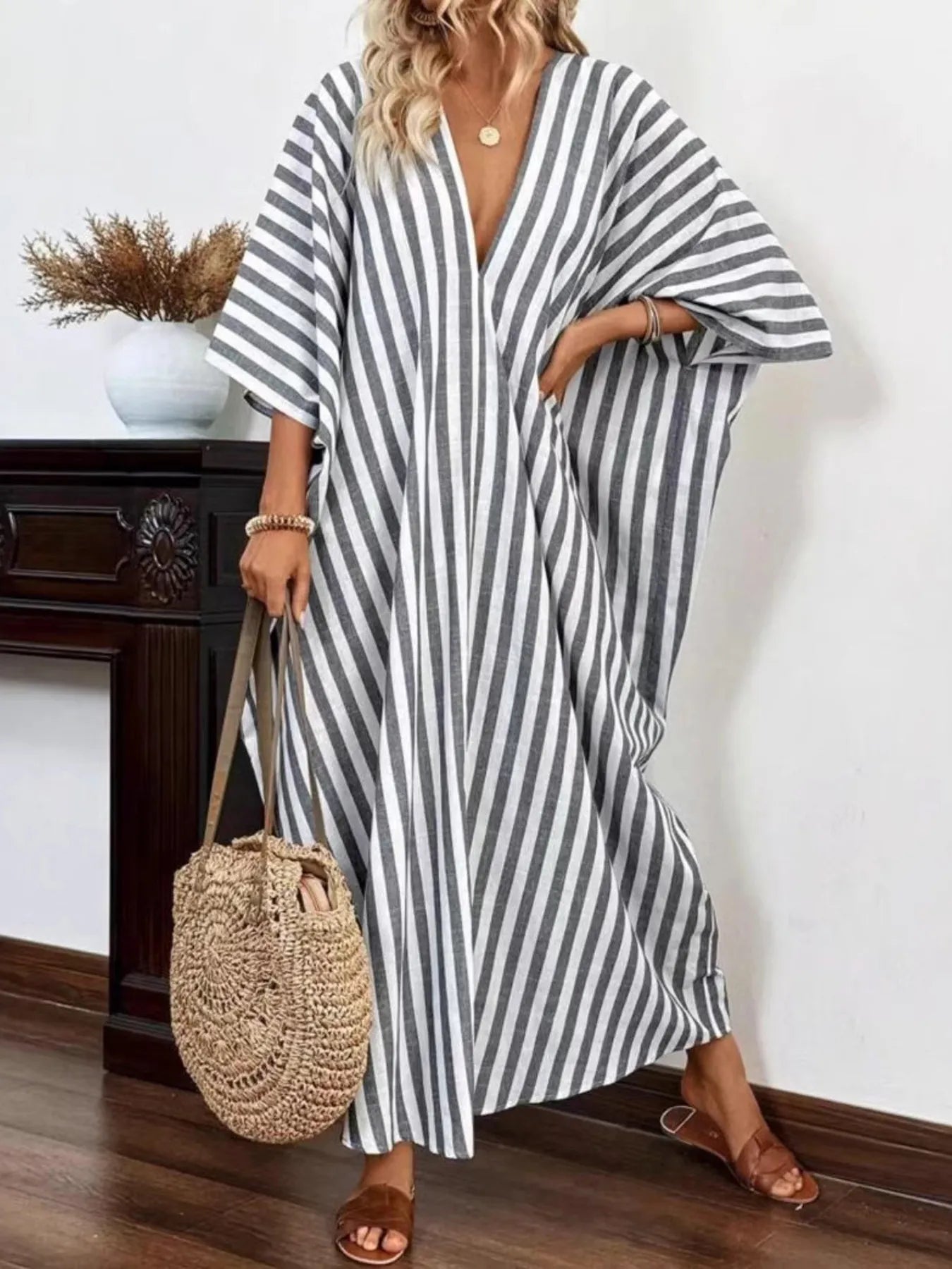 A woman rocking a chic gray and white striped maxi dress with a V-neck and loose sleeves.