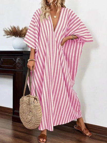 A woman rocking a pink and white striped maxi dress with a V-neck and loose sleeves.