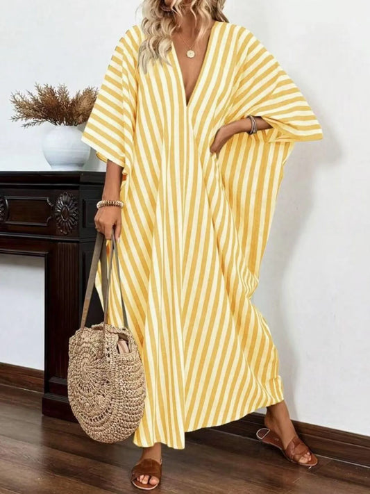 A woman rocking a yellow and white striped maxi dress with a V-neck and loose sleeves.