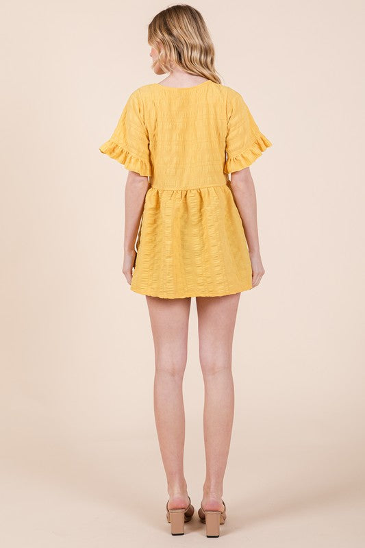 The textured weave gives depth while ruffles frame the shoulders.