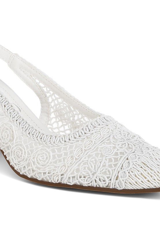 a  white stylish women's shoe with a closed, almond toe and an intricate lace-like upper in a light beige color.