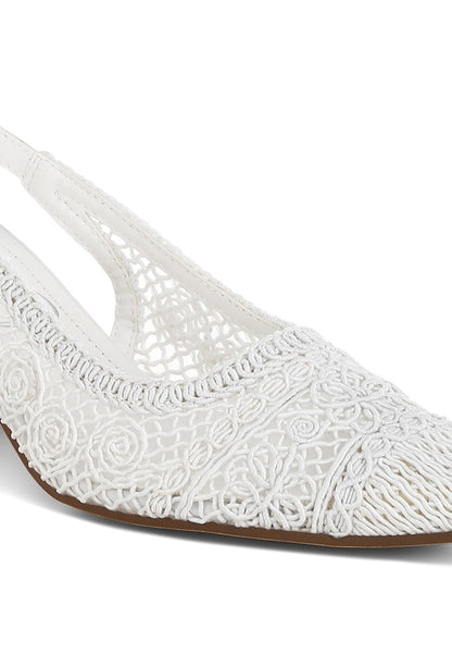 a  white stylish women's shoe with a closed, almond toe and an intricate lace-like upper in a light beige color.