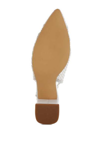 a stylish women's shoe with a closed, almond toe and an intricate lace-like upper in a light beige color.