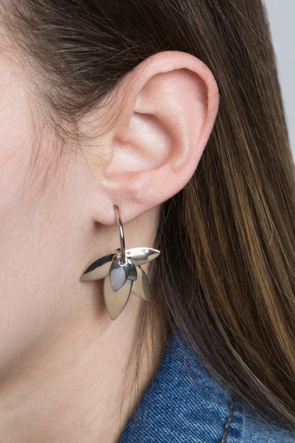 Balance in bloom. The Two-Tone Lotus Hoop Earrings blend the serenity of lotus symbolism with the boldness of mixed metals. Featuring a graceful lotus motif suspended within sleek hoops, these earrings are perfect for grounding your style with elegance and intention.