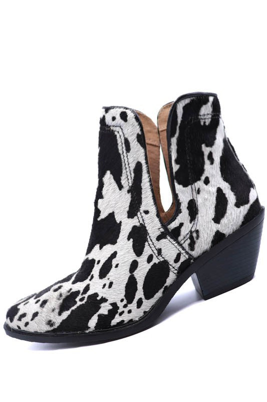 Western ankle booties featuring cow print hair-on-hide texture, pointed toe, chunky stacked heel, and side zip entry