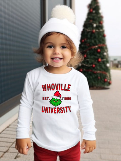 Child wearing a white sweatshirt with 'WHOVILLE UNIVERSITY' text, standing in front of a Christmas tree.
