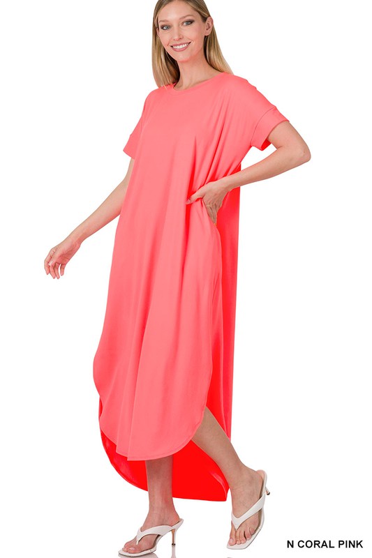 A bright coral-pink oversized dress with short sleeves and a loose, draped silhouette that falls to about knee or mid-calf length.