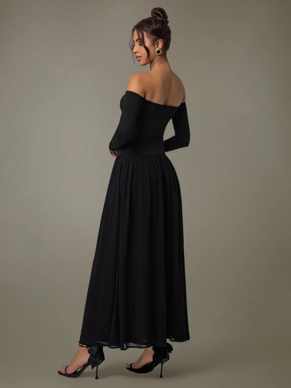 A floor-length black off-shoulder gown with a fitted bodice and voluminous skirt.