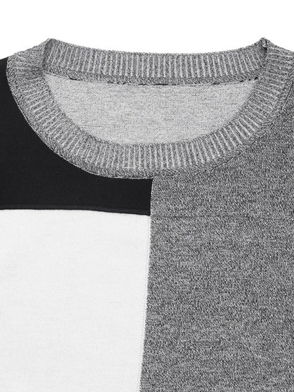 Close-up of a color block sweater with a ribbed crew neck and sections of black, white, and speckled gray fabric.