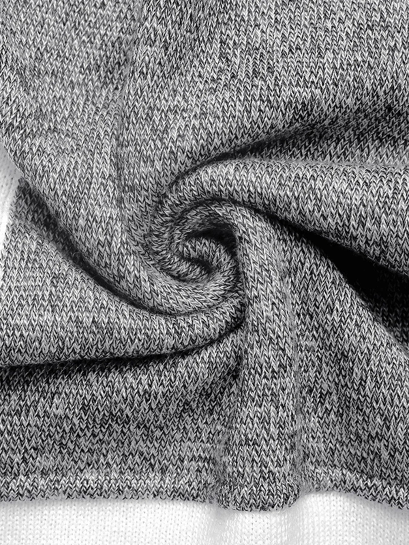 Close-up of a color block sweater with a ribbed crew neck and sections of black, white, and speckled gray fabric, twisted fabric.