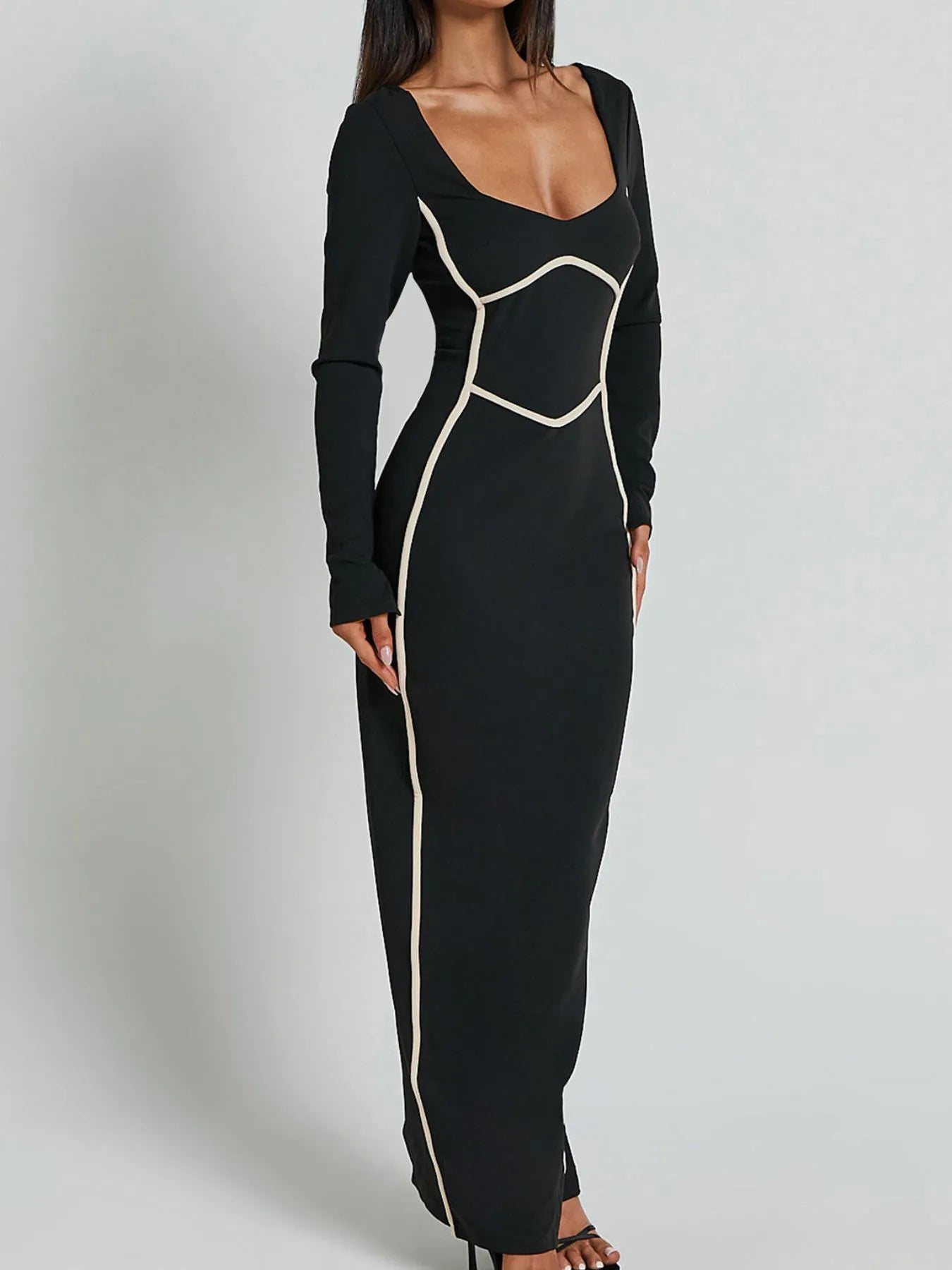 A full length form black dress with long sleeves and white trim details and has a geometric white pattern around the waist and shoulders.