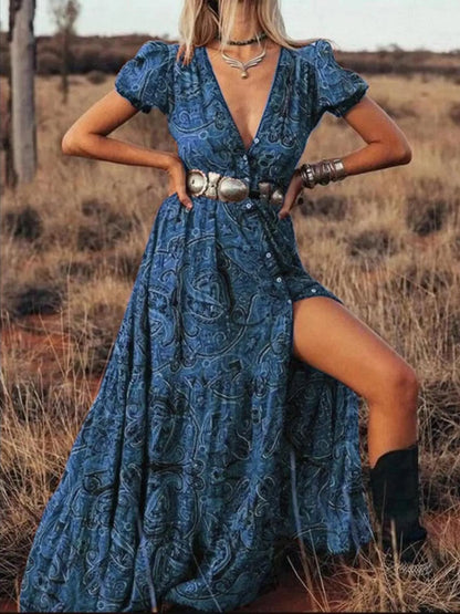 Woman wearing a flowing paisley print dress with puff sleeves, deep V-neckline, and high slit