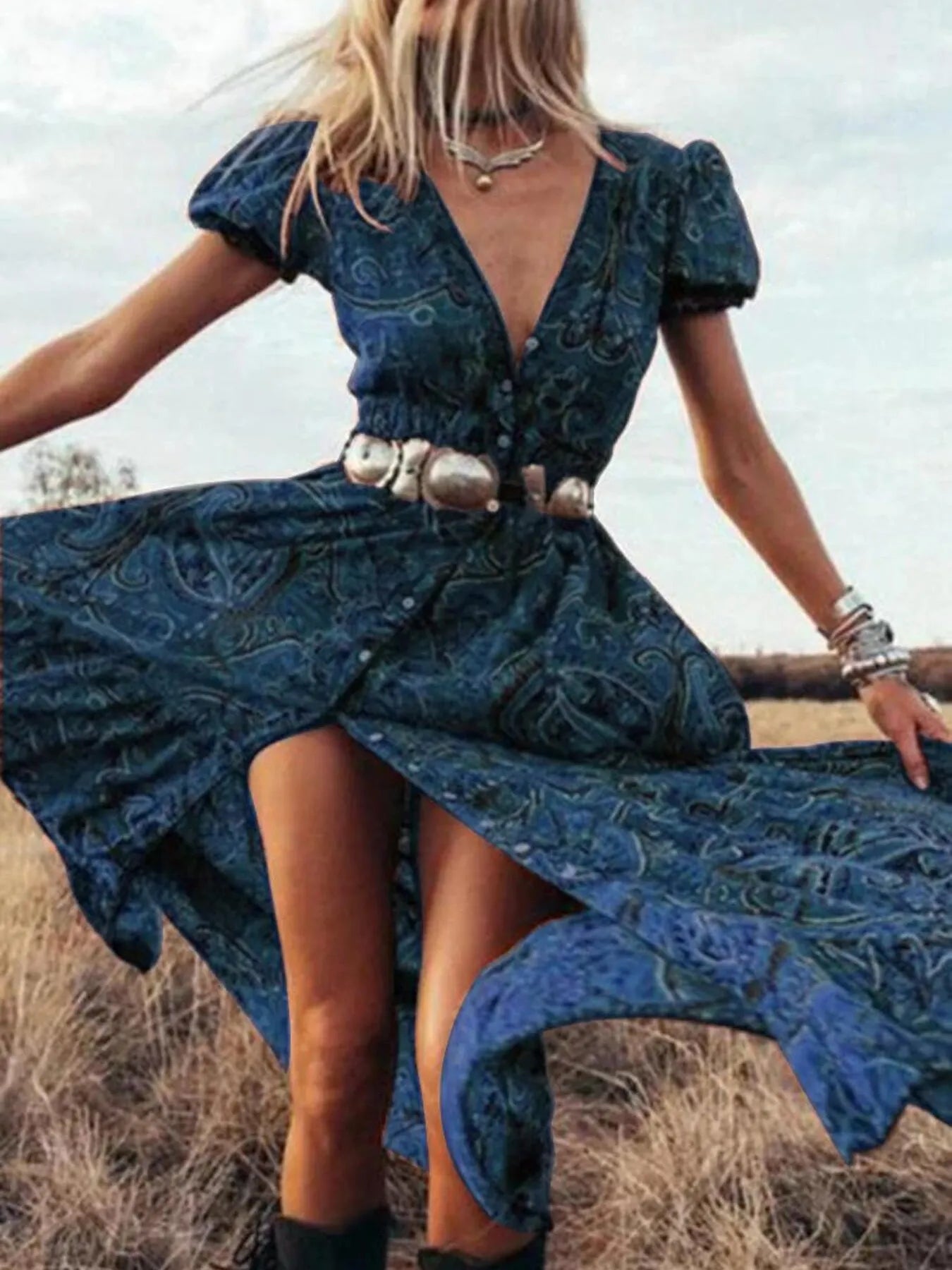 Woman wearing a black and white striped short-sleeve shift mini dress with ruffled sleeves, standing by a wooden door holding a straw hat.

