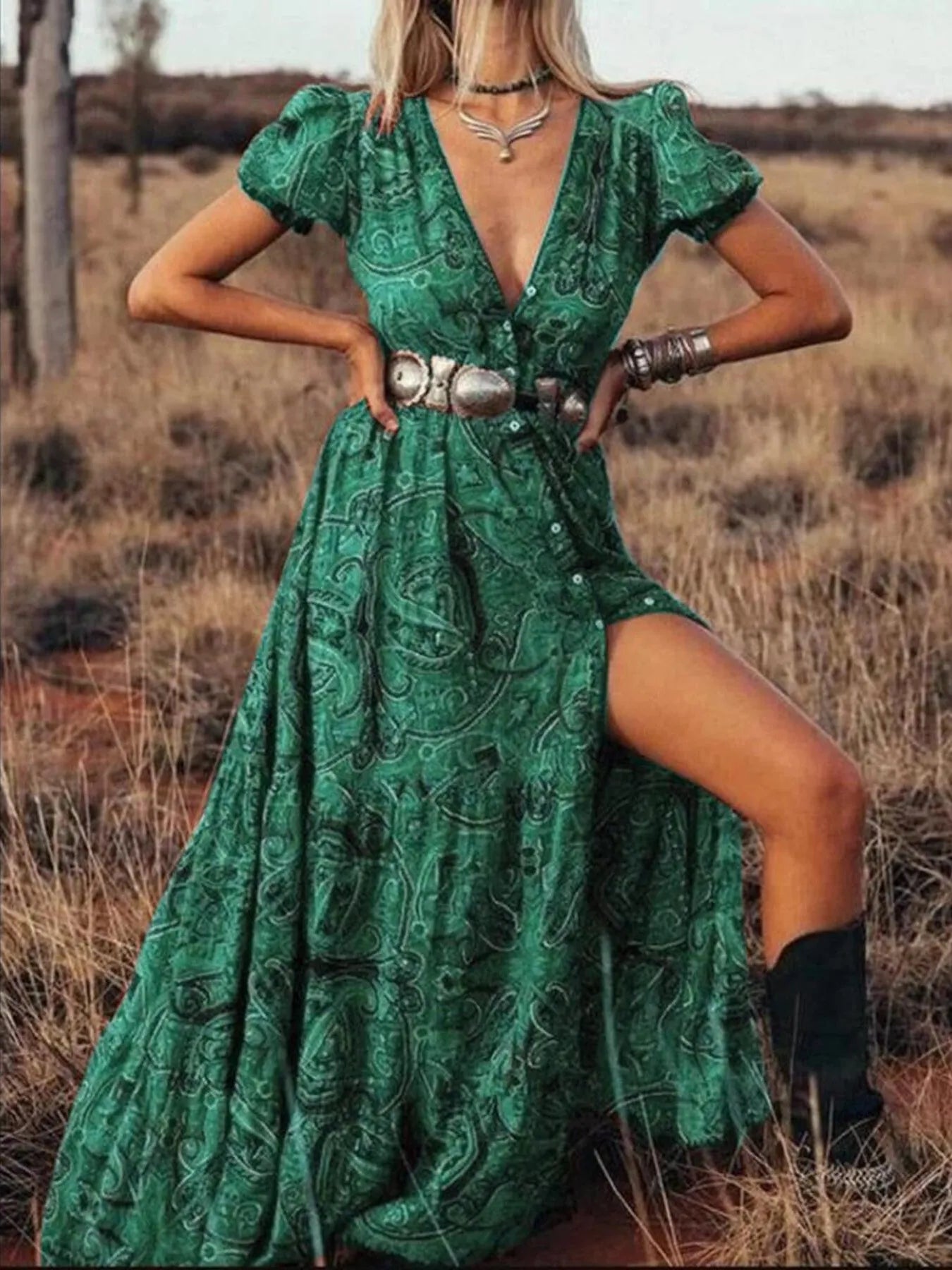 Woman wearing a flowing paisley print dress with puff sleeves, deep V-neckline, and high slit
