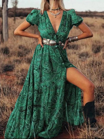 Woman wearing a flowing paisley print dress with puff sleeves, deep V-neckline, and high slit
