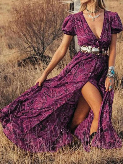 Woman wearing a flowing paisley print dress with puff sleeves, deep V-neckline, and high slit
