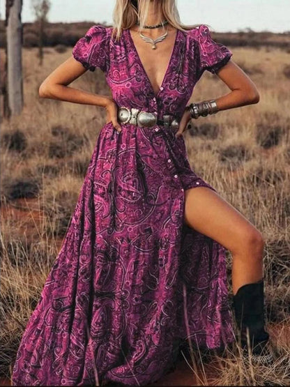Woman wearing a flowing paisley print dress with puff sleeves, deep V-neckline, and high slit

