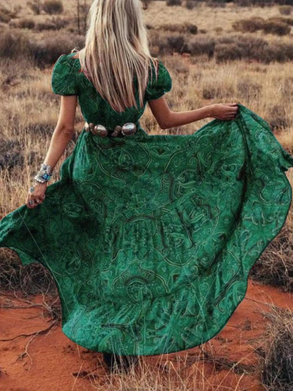 Woman wearing a flowing paisley print dress with puff sleeves, deep V-neckline, and high slit
