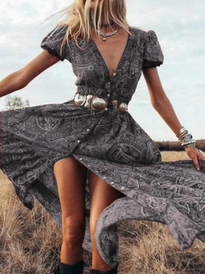 Woman wearing a flowing paisley print dress with puff sleeves, deep V-neckline, and high slit
