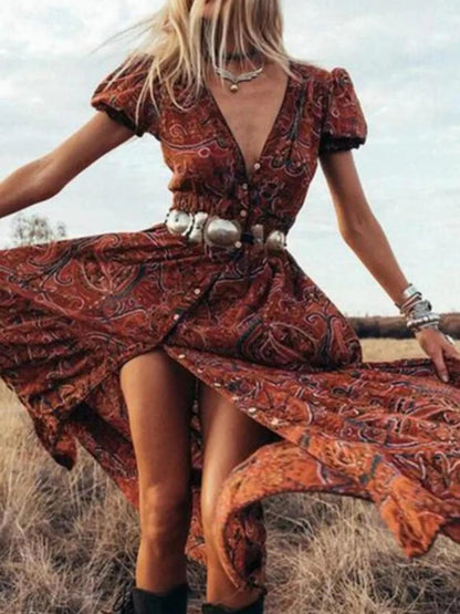 Woman wearing a flowing paisley print dress with puff sleeves, deep V-neckline, and high slit
