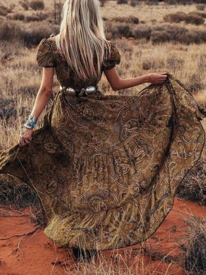 Woman wearing a flowing paisley print dress with puff sleeves, deep V-neckline, and high slit
