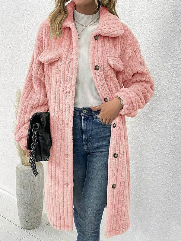 Person wearing a pink fluffy coat with a white wall background