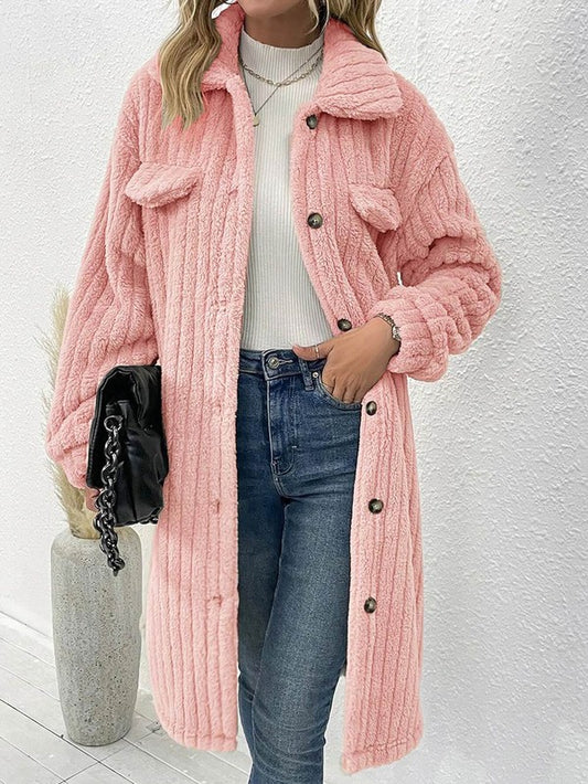 Person wearing a pink fluffy coat with a white wall background
