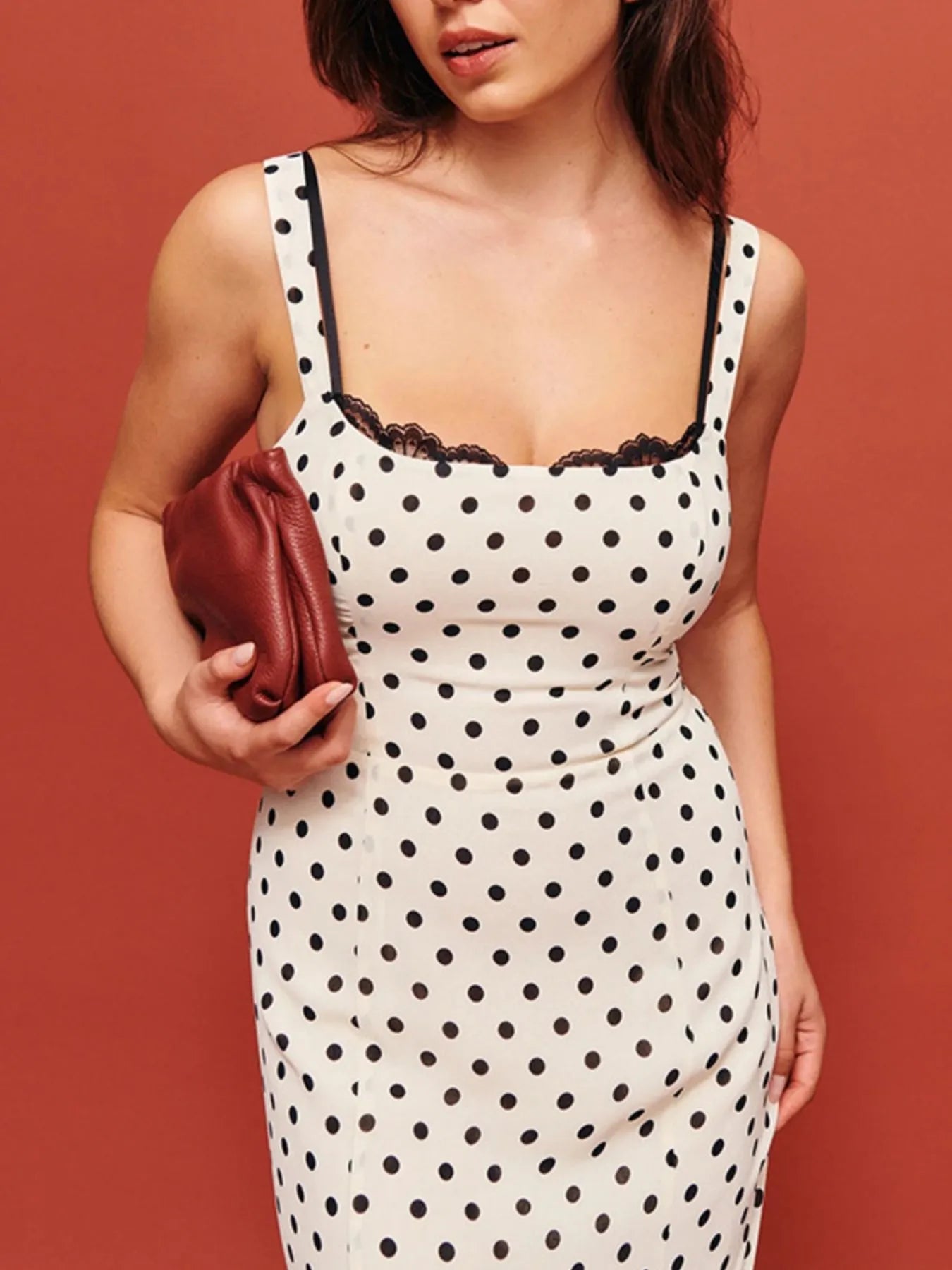A white, polka-dotted, sleeveless maxi with a fitted bodice and a flared, ruffled hem that reaches the ankles.