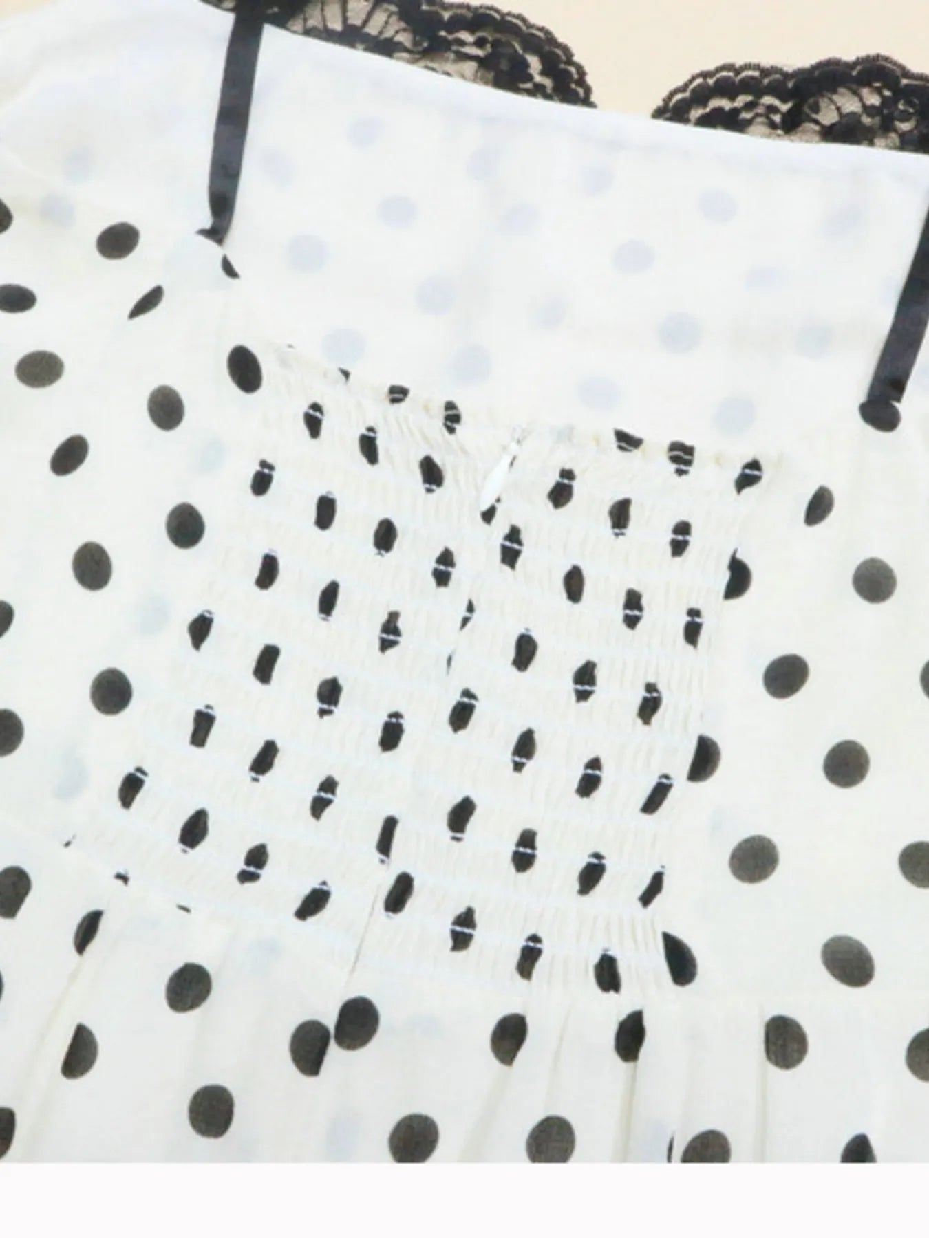 A white, polka-dotted, sleeveless maxi with a fitted bodice and a flared, ruffled hem that reaches the ankles