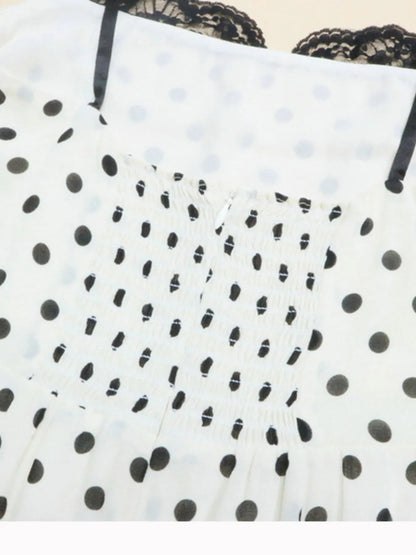 A white, polka-dotted, sleeveless maxi with a fitted bodice and a flared, ruffled hem that reaches the ankles