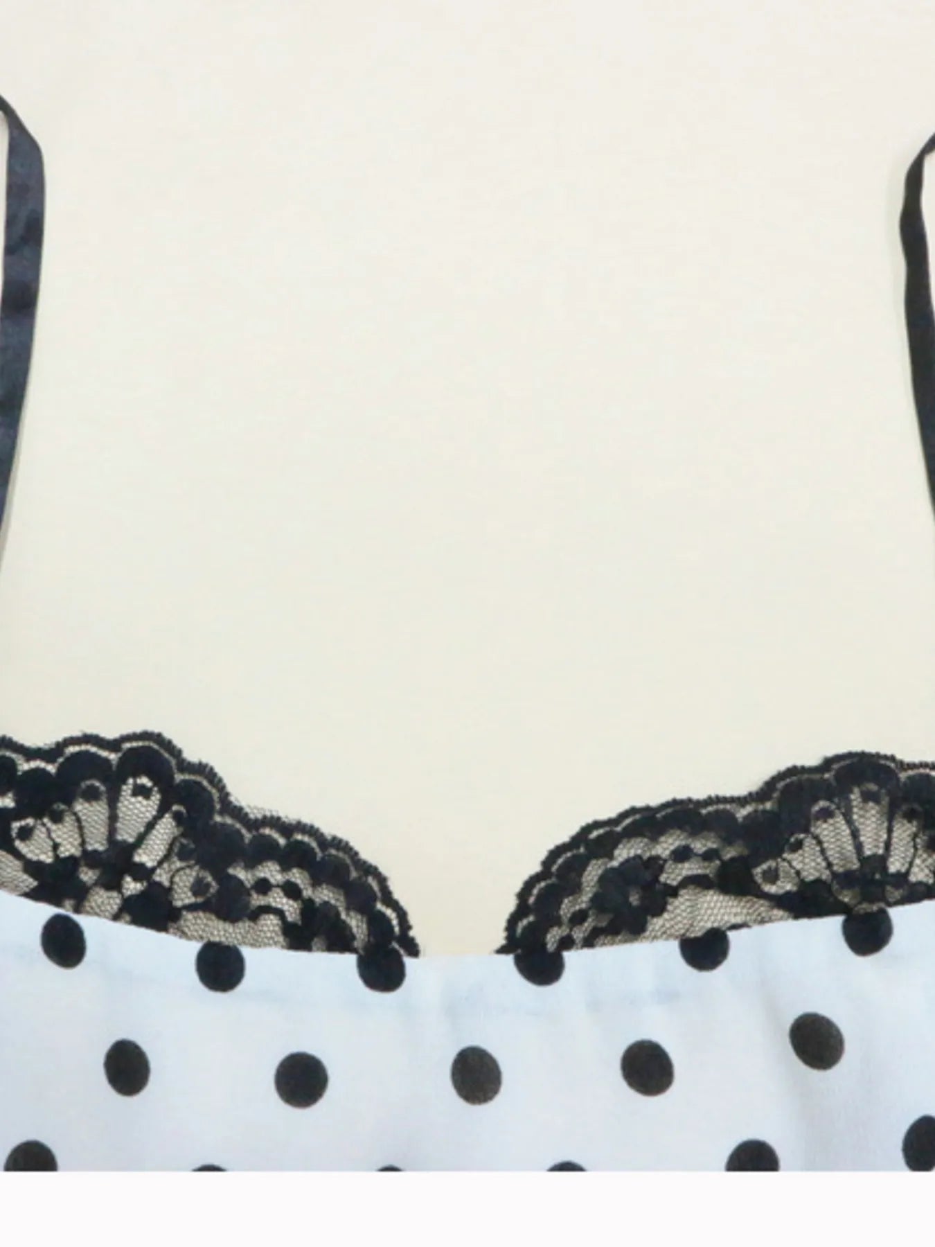 A white, polka-dotted, sleeveless maxi with a fitted bodice and a flared, ruffled hem that reaches the ankles