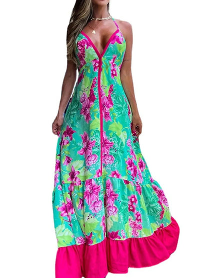 Woman wearing a floral halter-neck maxi dress with deep V-neckline and solid trim, standing by a tropical infinity pool
