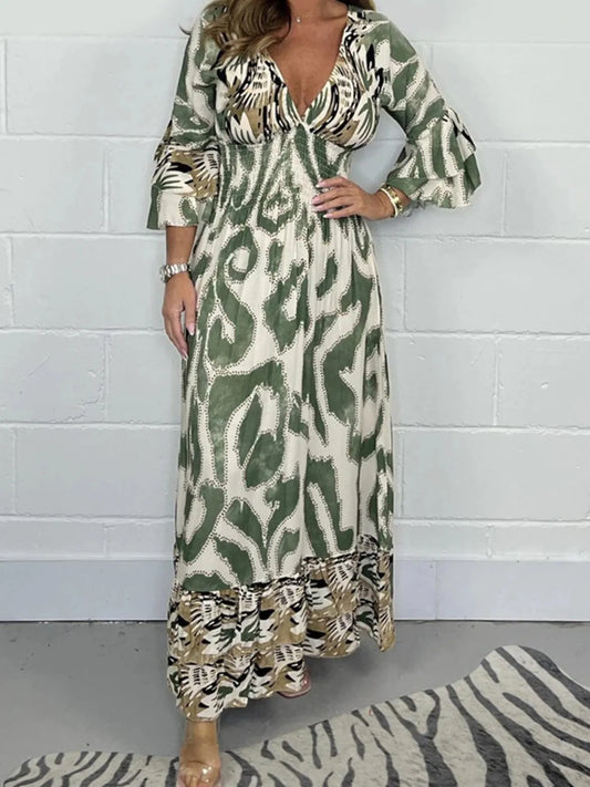Woman wearing a full-length printed V-neck maxi dress with long flared sleeves and mixed abstract and animal patterns, styled with open-toe heels.