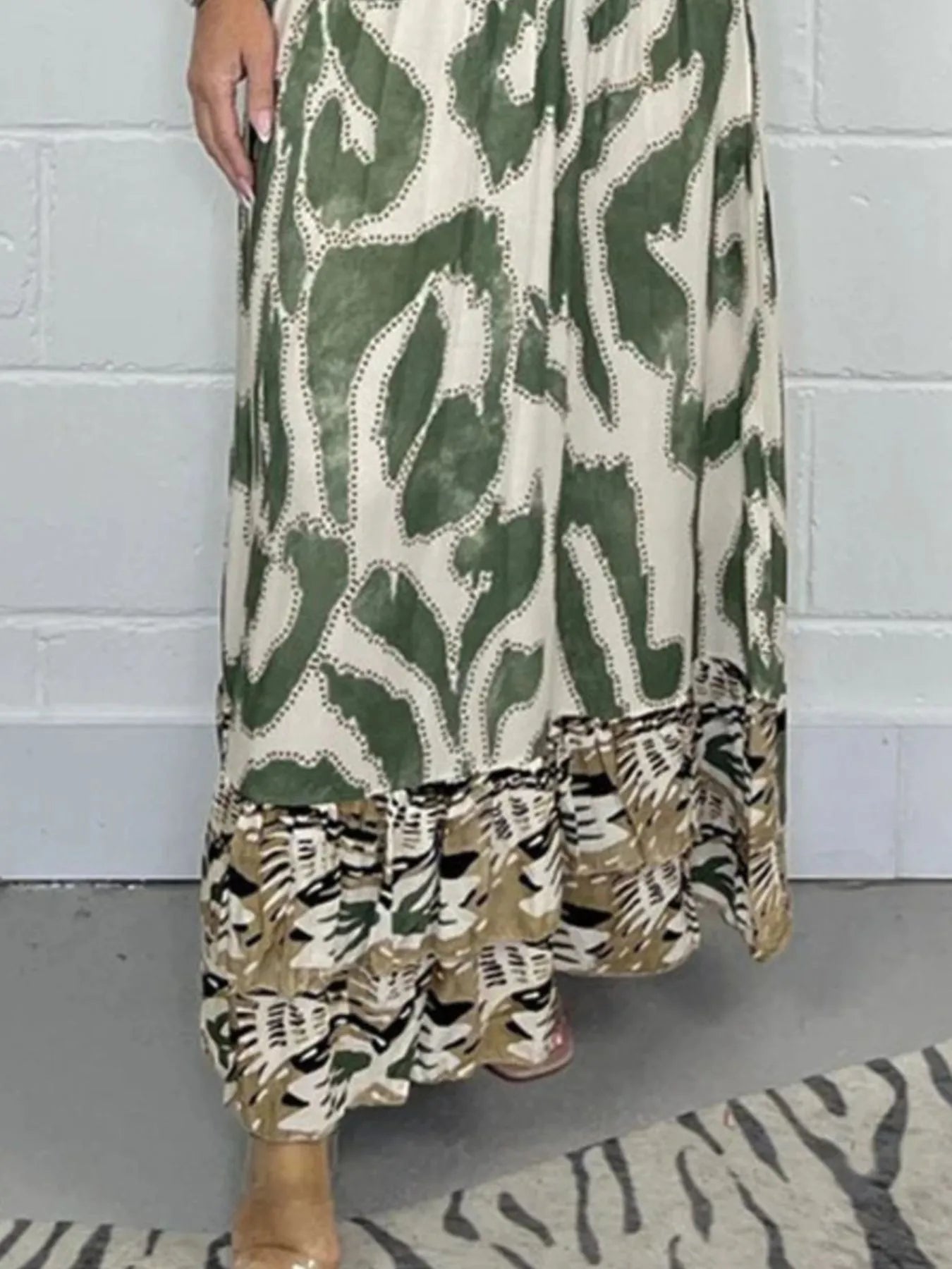 Woman wearing a full-length printed V-neck maxi dress with long flared sleeves and mixed abstract and animal patterns, styled with open-toe heels.b3da-Max-Origin