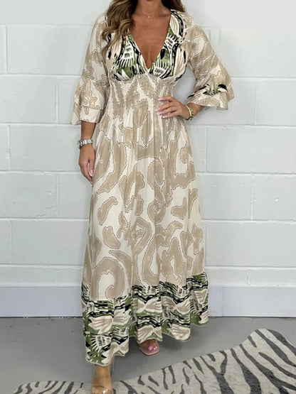 Woman wearing a full-length printed V-neck maxi dress with long flared sleeves and mixed abstract and animal patterns, styled with open-toe heels.