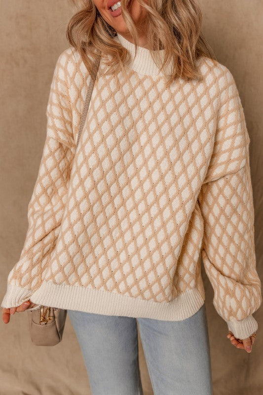 Woman wearing a beige and cream rhombus texture sweater with a mock neck and dropped shoulders.