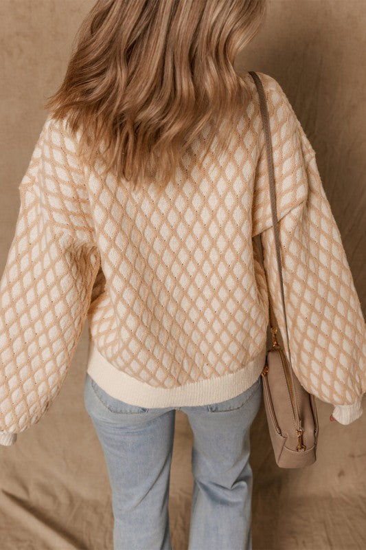 Woman wearing a beige and cream rhombus texture sweater with a mock neck and dropped shoulders, back view.