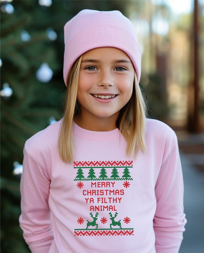 Child wearing a pink Christmas-themed sweater with text and graphics outdoors.