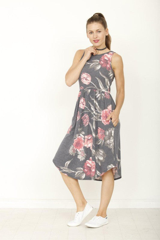 Woman poses in a stylish sleeveless floral midi dress with pink flower print, featuring a flattering gathered waist and practical pockets